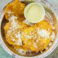 Tostones · Fried green plantains topped with herb, garlic mayo and cojita cheese.