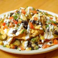 Nachos · Tortilla chips with guacamole, roasted corn, black beans, cheese sauce, pico de gallo, pickl...