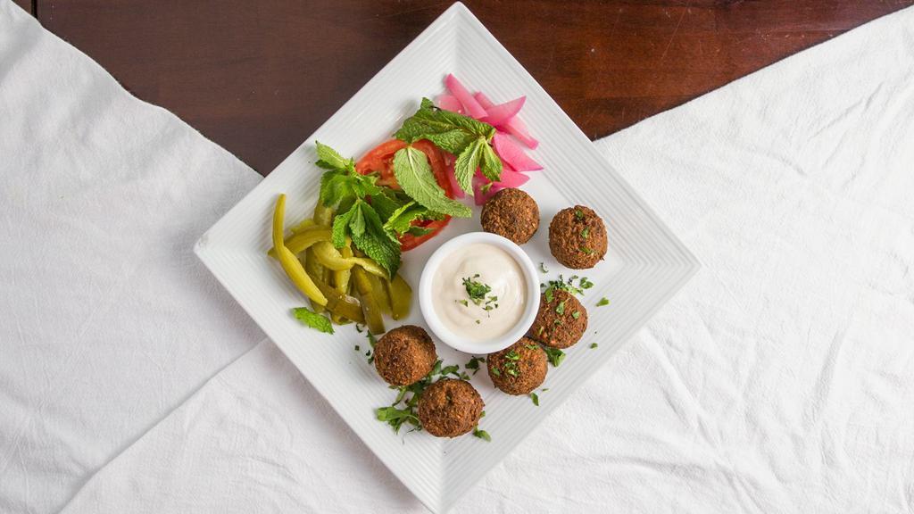 Falafel · Chickpeas and fava bean balls spiced to perfection. Served with tahini sauce, turnips, tomato and fresh mint.