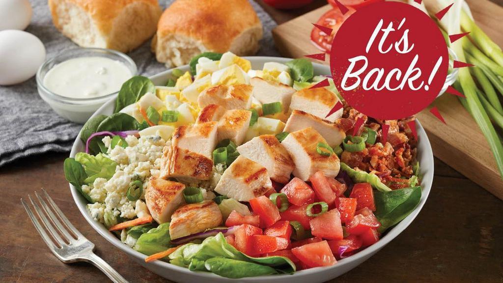 Grilled Chicken Cobb Salad · Grilled chicken, crispy bacon, hard boiled eggs, fresh-diced tomatoes and green onions on a bed of greens, topped with real blue cheese crumbles. Served with blue cheese dressing.