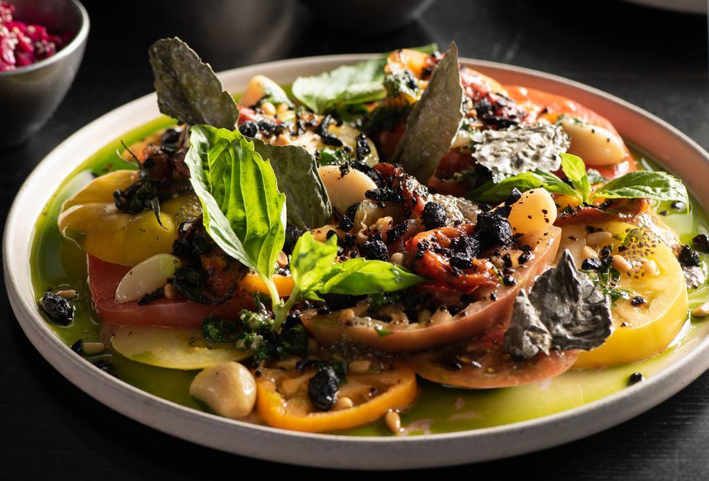 Salat Aviv · Heirloom Tomatoes, Moroccan Black Olive Crumble, EVOO, Confit Garlic, Grilled & Confit Bell Pepper, Arabic Salsa, Roasted Pine Nuts, Basil Oil, Basil Chip, Pesto