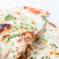 Garlic Naan · Leavened bread touched with fresh shredded garlic and herbs then baked in our Clay Oven.