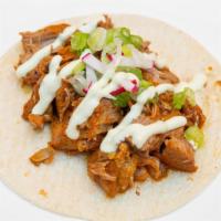 Cochinita · Spicy aromatic slow-cooked pork served with Mexican crema, spring onion, and baby radish.