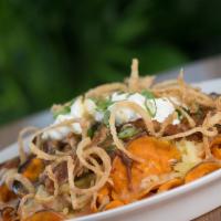 Sweet Potato Nachos · Apple butter bbq pulled pork, white cheddar, onion fritters, green chili, crema.
