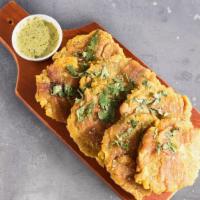 Tostones · Fried green plantains served with green chimichurri.