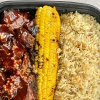 Beef Ribs Platter · Giant Texas style Beef rib served with rice, roasted corn, and hardough bread.