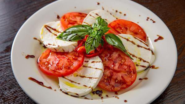 Caprese Salad · Homemade fresh mozzarella cheese, tomatoes, roasted red peppers, basil and extra virgin olive oil, drizzled with balsamic vinegar reduction.