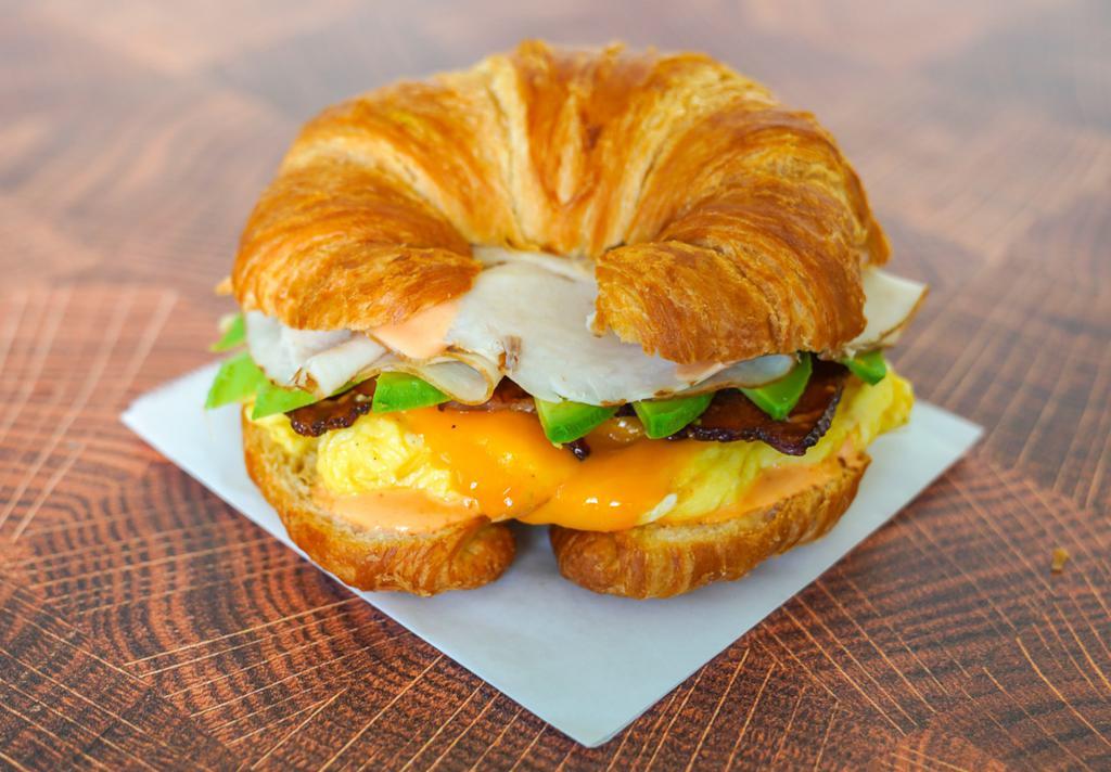 Croissant, Bacon, Turkey, Avocado, Egg, & Cheddar Sandwich via