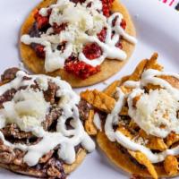 Steak Picaditas · Three pieces. Fresh thick soft corn tortilla coated with re-fried beans. Topped with our hom...