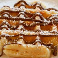 Nutella Waffle · Golden Belgien waffle topped with a Nutella drizzle and served with a side of maple syrup.