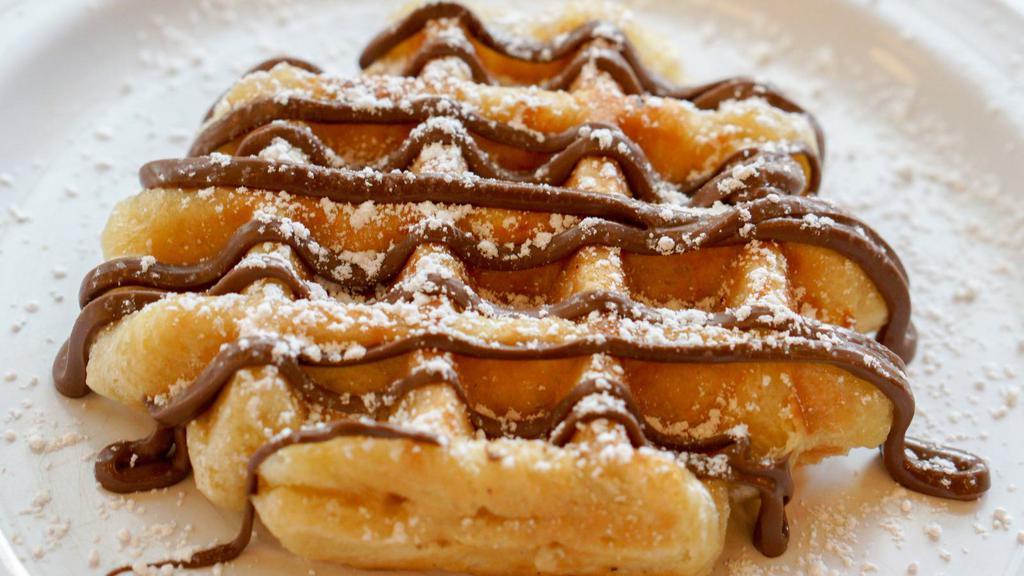 Nutella Waffle · Golden Belgien waffle topped with a Nutella drizzle and served with a side of maple syrup.