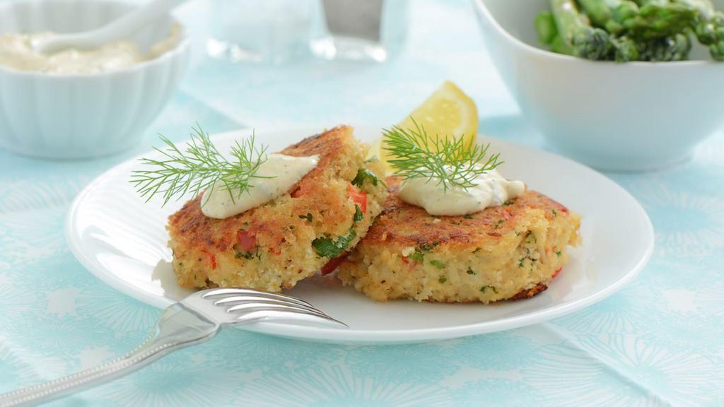 Crab Cakes · Patty stuffed with mouth watering crab meat, served with a drizzle of tartar sauce.