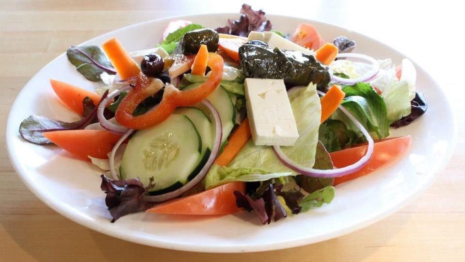 Greek Salad · Mixed greens, tomatoes, onions, peppers, kalamata olives, feta cheese, anchovies, cucumbers, stuffed grape leaves and Greek vinaigrette dressing, served with pita bread.