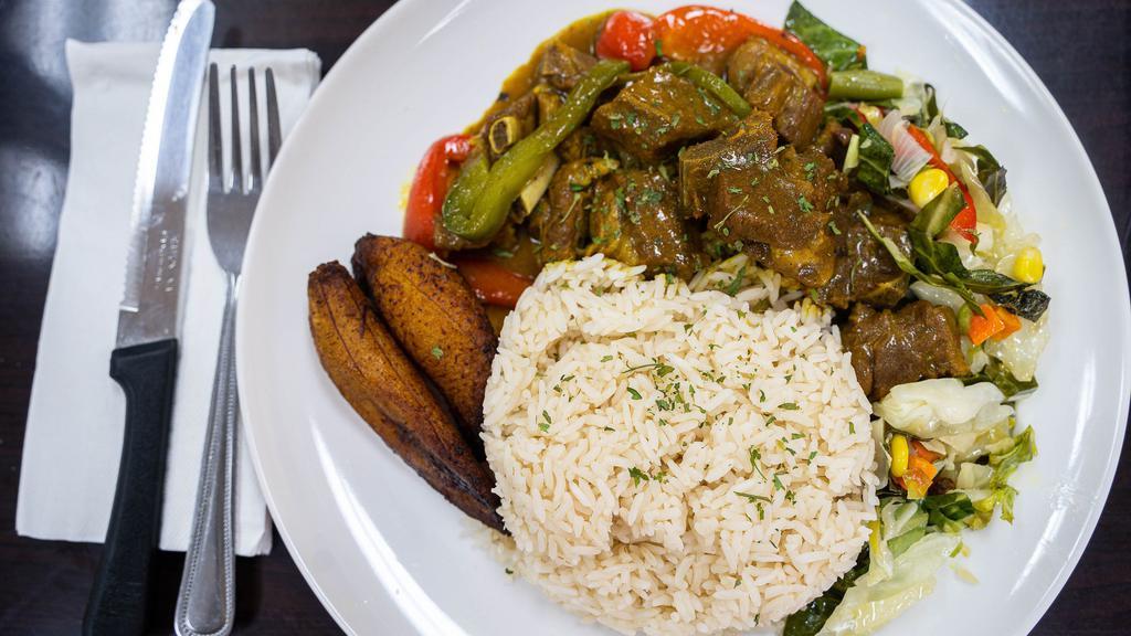 Curry Goat · Medium size serving of curry goat with white rice or rice and peas, steamed vegetables and plantains