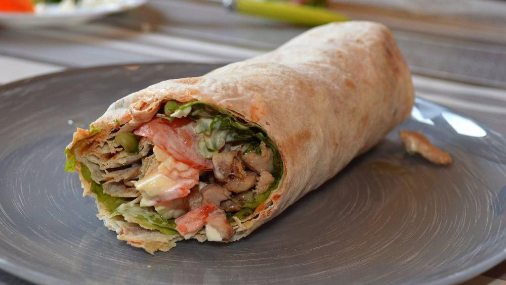 Chicken Shawarma Sandwich · Grilled strips of seasoned chicken breast with tahini sauce, hummus spread, and lettuce on wrap served with cucumber salad.