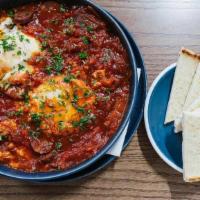Chorizo Baked Eggs · Eggs baked in a tomato sauce with onion, peperoncini, & Spanish chorizo, served with warm pi...