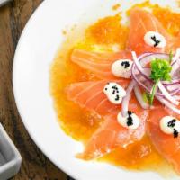 Salmon Carpaccio · Thinly sliced king salmon sashimi, red onions, garnished with a creamy ginger sauce and tobi...