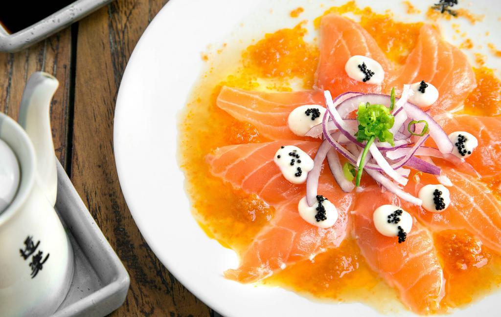 Salmon Carpaccio · Thinly sliced king salmon sashimi, red onions, garnished with a creamy ginger sauce and tobiko.