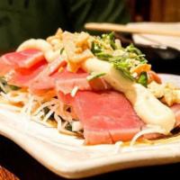 Doraku Tuna Tataki · Seared tuna served over a wakame daikon salad, garnished with garlic aioli and ponzu sauce.