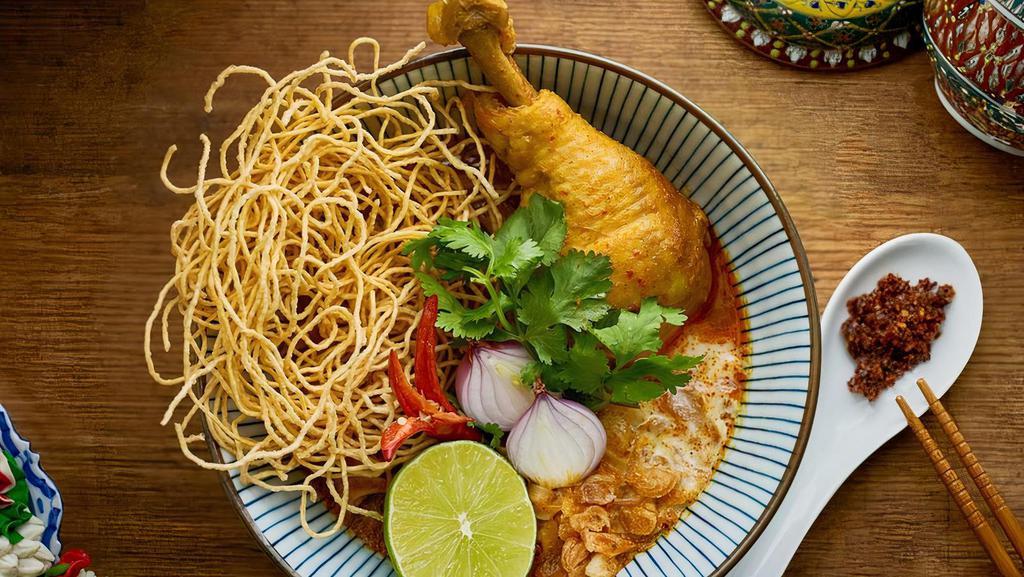 Khao Soi Kai (Chicken) · Northern Thai style steamed egg noodles with khao soi curry, braised chicken drumstick, red onions, fresh lime and crispy egg noodles.