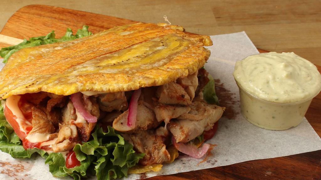 Grilled Chicken Patacon · Green Plantain Sandwich allied With Grilled Chicken, grilled Cheese, lettuce, tomatoes, pink sauce and ketchup.