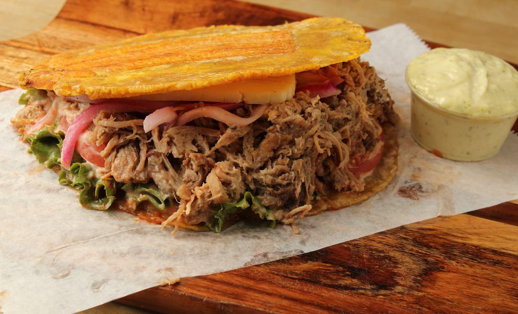 Pernil Patacones · Roasted pork. A sandwich made with slices of twice fried green plantains instead of bread, with fried cheese, the meat of your choice, lettuce, and tomatoes.