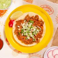 Cochinita Pibil Taco · Slow roasted pork shoulder topped with cilantro and chopped onion on a soft corn tortilla.