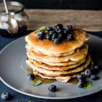 Blueberry Buttermilk Pancakes · 4 perfectly fluffy blueberry pancakes served with a side of butter and syrup.