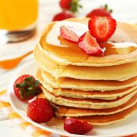 Strawberry Buttermilk Pancakes · 3 pcs fresh buttermilk pancakes topped with strawberries with a side of butter and syrup.