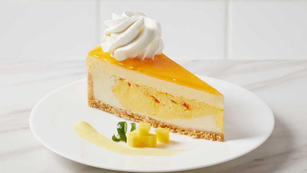 Mango Key Lime Cheesecake · Mango key lime cheesecake swirled with mango and topped with a mango mousse and glaze, on a coconut vanilla crumb, finished with whipped cream rosettes.