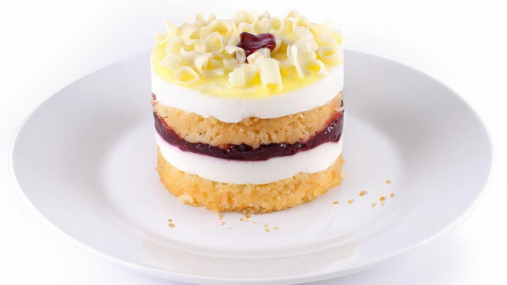 New! Raspberry Lemon Drop · Light & refreshing! Yellow sponge cake is layered with lemon mousse and thick raspberry preserves. Finished with a bright lemon glaze and mini white chocolate curls.