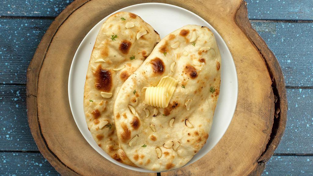 Genius Garlic Naan · Freshly baked bread in a clay oven garnished with garlic and butter