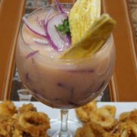Leche De Tigre  · Shrimp perched on martini glasses containing a Ceviche's juice with chunks of fish
