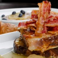 French Toast With Side Of Bacon · Custard-dipped, thick-cut brioche bread topped with crispy bacon, whipped butter, and syrup.