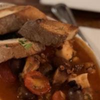 Polpo Alla Luciana · Sauteed Octopus with capers, black olives in a tomato sauce over country bread.