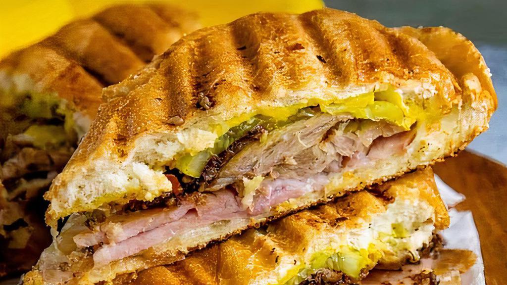Cubano Sándwich · Braised pork, sliced ham, Swiss cheese, dill pickle, garlic aioli, in a roll.