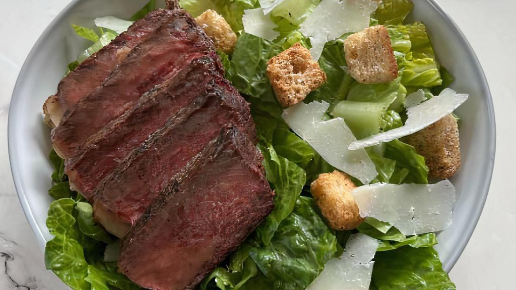 Steak Caesar Salad · Steak served on a bed of Romaine lettuce, shaved pecorino romano, herbed croutons, with a side of caesar dressing.