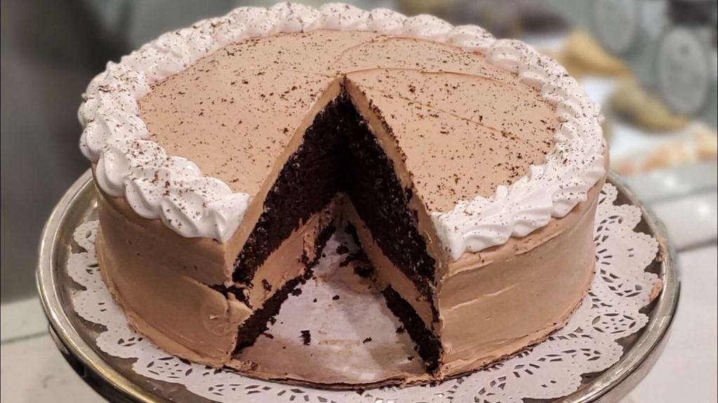 Mocha Cake Slice · rich chocolate cake infused with espresso, accompanied by a fluffy mocha buttercream and topped with flourishes of meringue.