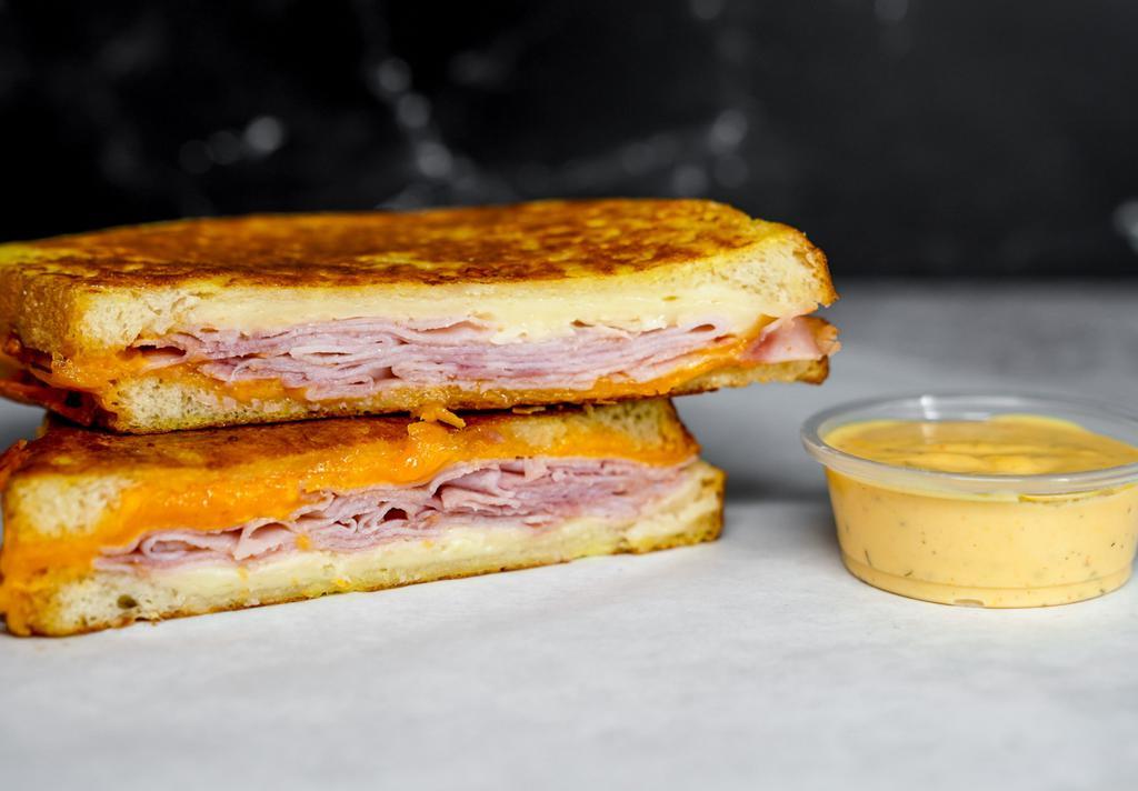 Smoked Ham & Three Monte Cristo · Smoked ham, Cheddar, Swiss, and Parmesan cheeses melted between egg dipped, griddled sourdough bread. Served with a side of Spicy Honey Mustard Aioli.