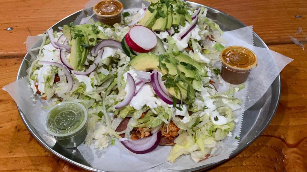 Tinga Tostadas · Tinga = Shredded chicken cooked with onions.
Three per order, lettuce, avocado, onions, salsa, refried beans, cheese.