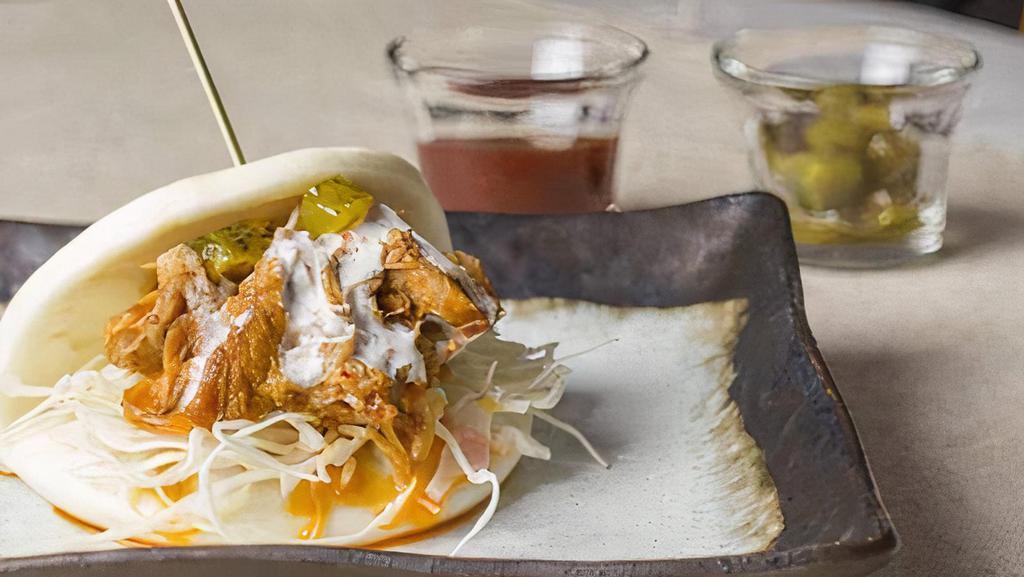Spicy Pork Bun · Spicy pulled pork bun with cabbage, honey pickle, and lime sour cream sauce