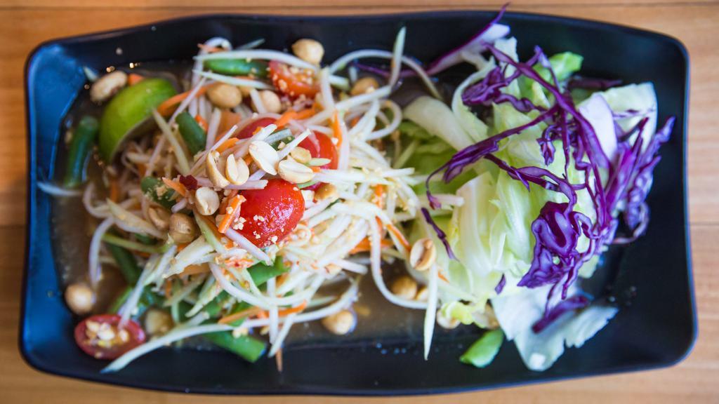 Papaya Salad · Spicy. Shredded green papaya and carrot served with bird chilies, garlic, peanuts, tomatoes, string bean, and lime.