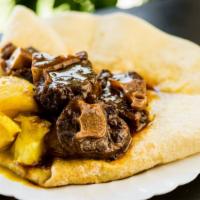 Oxtail Roti · Stewed and simmered, tender, bone-in oxtail with potato  in a paratha style roti.