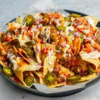Nachos · A bed of crisp tortilla chips is loaded with house chili and queso, drizzled in ancho chile ...