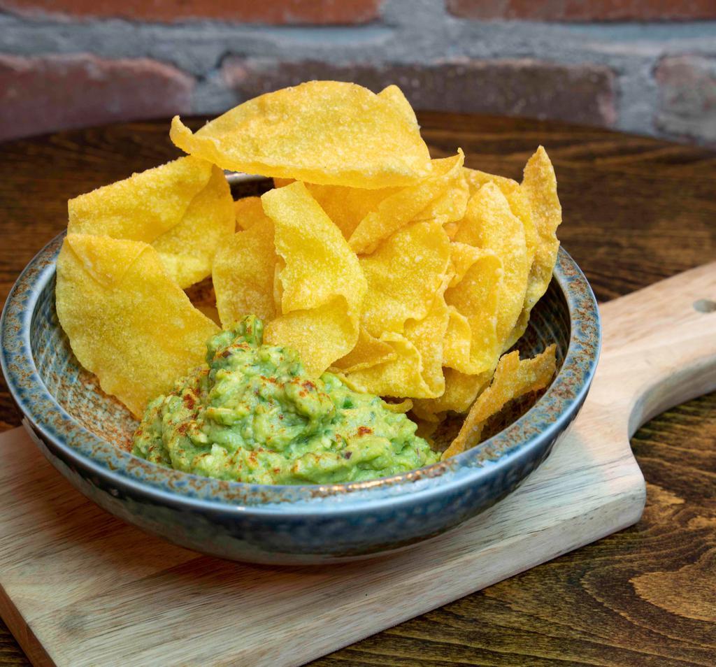 Guacamole And Chips · Guacamole is made with charred jalapeno, cilantro, tomato, red onions, lime, salt and pepper and served with Wonton Chips.