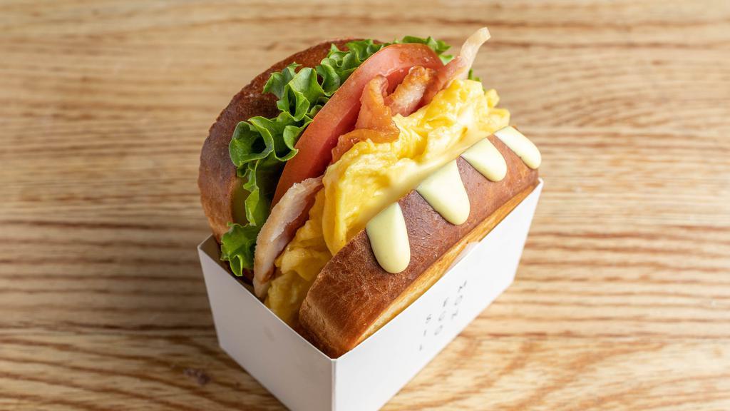 Bacon · - Toasted brioche bread - Green leaf lettuce - Tomato - Bacon - Scrambled eggs with grilled corn - Mustard mayo sauce.