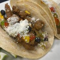Carne Asada Taco · citrus-marinated steak, salsa verde and our corn and black bean salsa topped with grated cot...