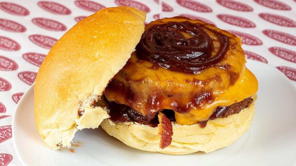 Cowboy Burger · Six ounces black angus, cheddar, bacon, onion rings, bbq sauce on a brioche bun.
