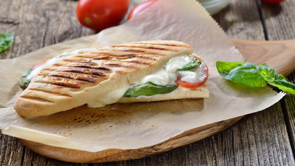 Fresh Mozzarella Panini · Delicious Panini made with Fresh mozzarella, spinach, basil and sun-dried tomatoes. Served on pressed European flatbread with chips and pickles.