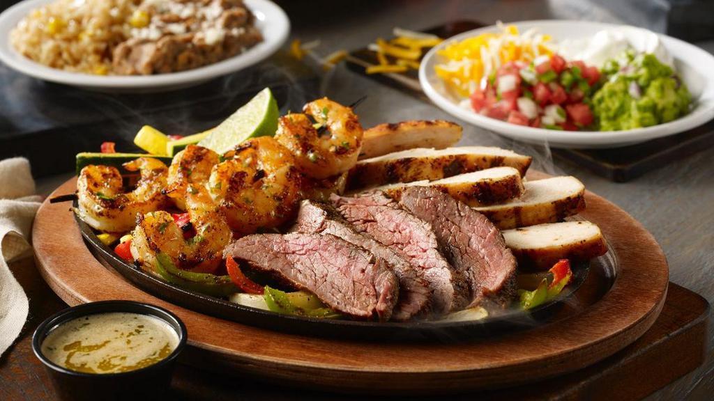 Grande Fajita Trio · The ultimate combo of mesquite-grilled steak, chicken and shrimp, with sautéed vegetables. Served with hand-pressed flour tortillas, pico de gallo, cheese, Mexican rice and choice of beans.